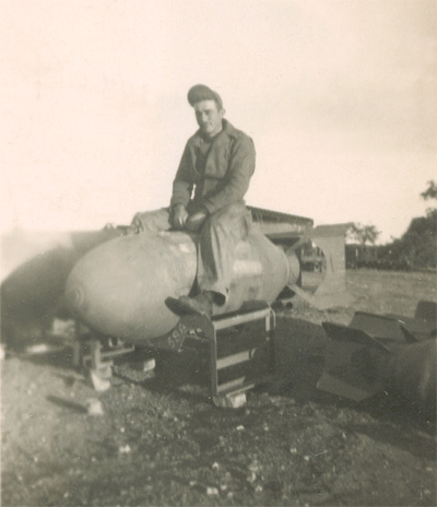 Unidentified man sitting on bomb. "Rivenhall, England" written on reverse